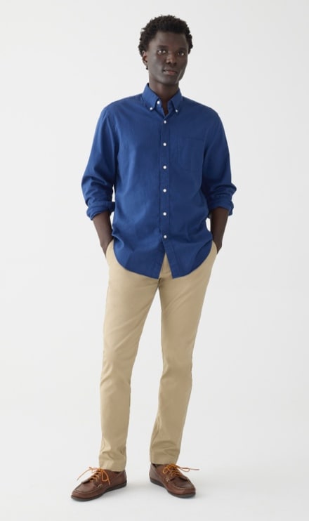 A handsome man in his 20s standing against a white background, wearing a blue  shirt tucked in to his khaki pants. Smiling towards camera. Stock Photo |  Adobe Stock