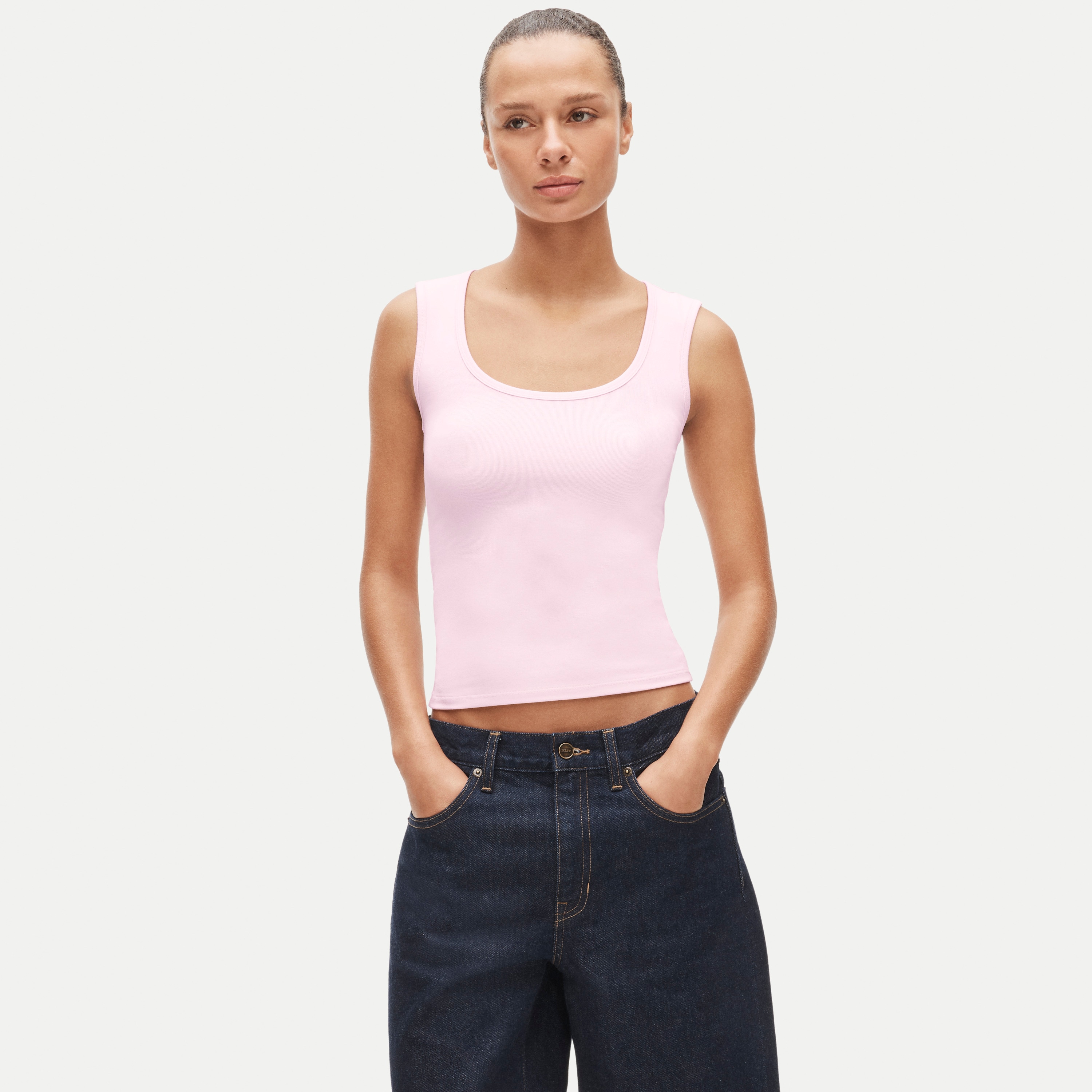 Woman wearing pink Refined rib scoopneck tank top paired with dark wash denim jeans.